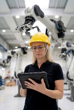 Female engineer inspect industrial machinery with tablet