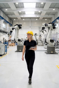 Woman engineer inspect industrial robot with tablet in factory