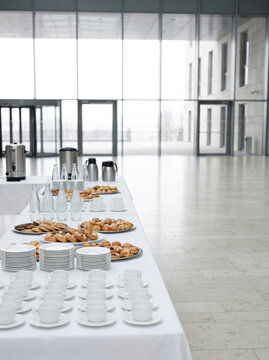 Conference catering tables set with cups, plates and pastries