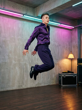 Dancer caught at the top of a jump in a neon-lit studio