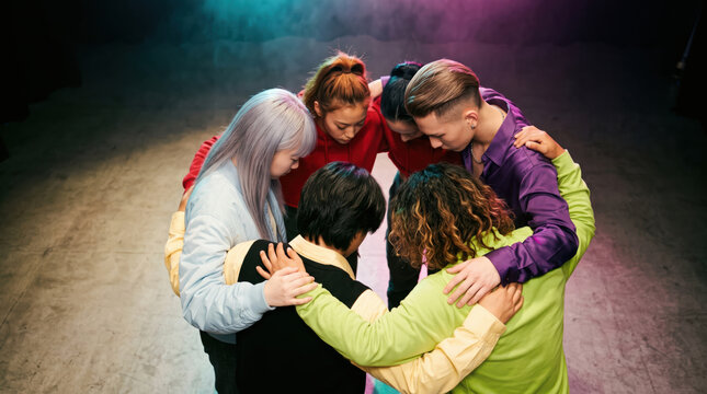 Performers in a tight huddle with heads down before going on