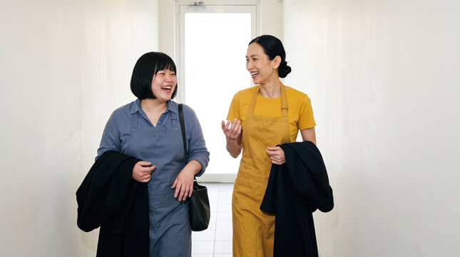 Asian chefs laugh together after work in restaurant hallway