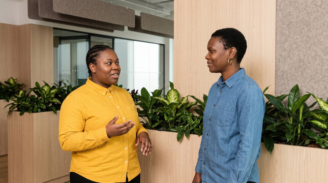 Black colleagues converse in modern office workspace