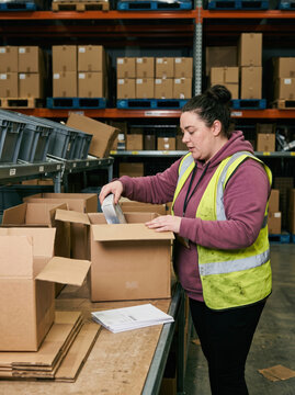 Warehouse worker inspect returned parcel at packing bench