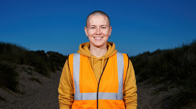 Smiling volunteer in safety vest at coastal cleanup site