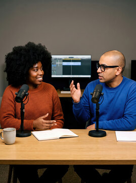 Podcast hosts discuss interview topics in recording studio