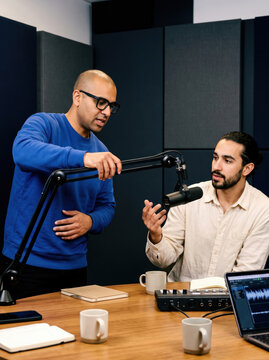 Podcast studio team adjust microphone during recording session