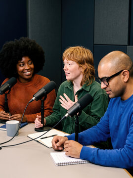Diverse hosts record conversation in a modern podcast studio