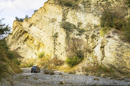 Dark 4WD car drives isolated in stunning rocky valley surounded by autumn nature. VAshlovani national park.Georgia