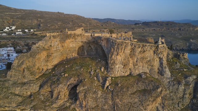 Drone shot, first morning light, Lindos, Acropolis of Lindos, Rocky cliffs with remains of an ancient fortress during the golden hour, Archaeological site, Lindos, Rhodes, Dodecanese, Greek Islands, Greece