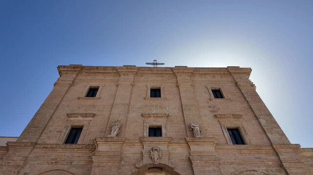  Close-up shot of the 18th-century facade of the Santa Maria de Finibus Terrae Sanctuary in Leuca, Salento, Apulia. Architectural details of the historic catholic basilica and main entrance under a cl