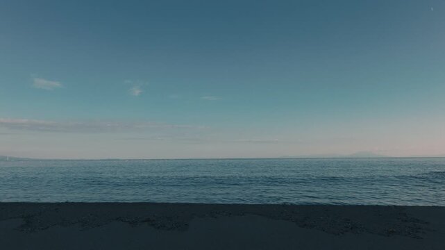 Gentle Waves Lapping Against a Blue-Gray Sandy Beach Beneath a Gradient Sky