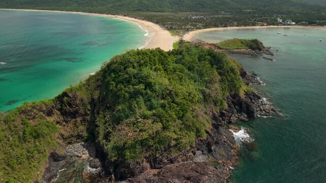 Drone footage over Nacpan and Calitang Twin Beach in El Nido, Palawan, capturing the distinctive shape of the two beaches, white sand shoreline and surrounding tropical landscape.