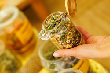 Fototapeta premium Hand holding glass jar with dried herbal tea mixture
