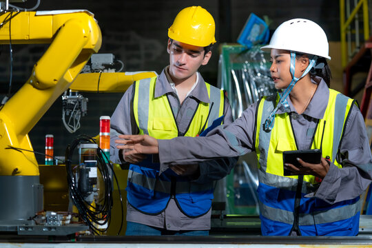 Engineers checking machinery operations on a factory floor highlighting smart manufacturing Industry 4.0 technology and teamwork in industrial engineering maintenance.