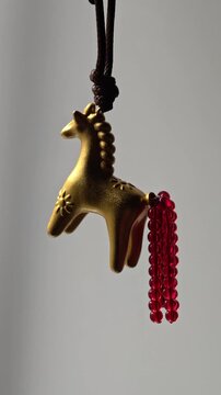 A gold horse ornament hanging from a string, ideal for decorating a tree or a room