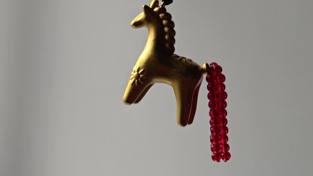 A gold giraffe ornament hanging from a red string, ideal for wedding decor, party favors, or photography props