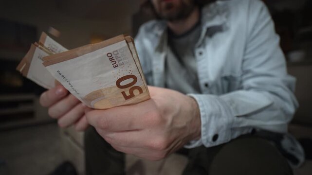 Man counting euro banknotes in his hands. Cash money, payment and personal finance concept. Person holding and checking European currency indoors