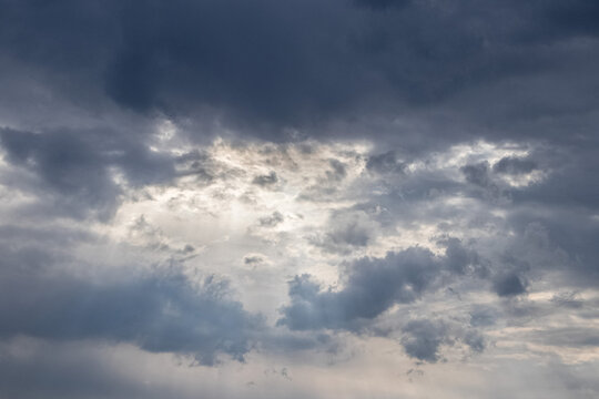 Dramatic sky with dark storm clouds and bright light breaking through dense blue and gray clouds