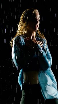 Beautiful blond woman hip-hop dancing in the rain. Slow Motion. Vertical video.