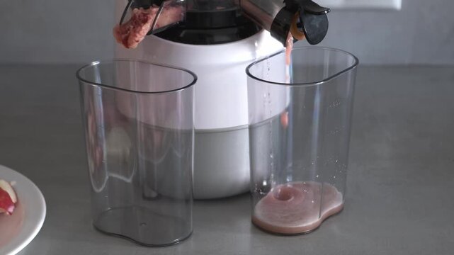 Fresh apple juice and dry pulp pouring from electric slow juicer extractors into containers, cold press machine close up