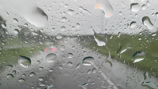 Heavy Rain on Car Windshield While Driving on Interstate Highway with Blurred Traffic in Background