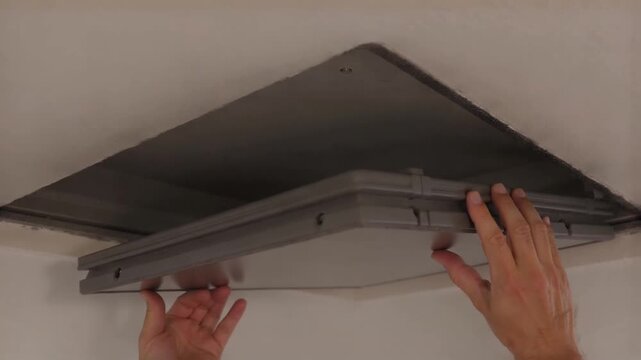 Hands closing a thick insulated attic hatch