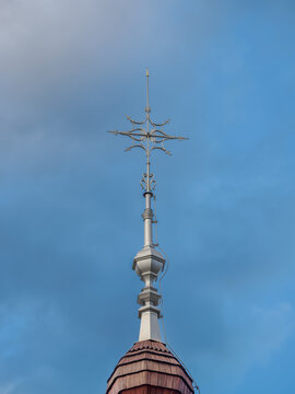 Metal snowflake cross on top of a church with a wooden roof.