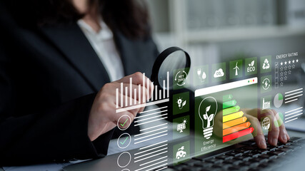 A business professional evaluates energy efficiency data using a modern digital interface,...
