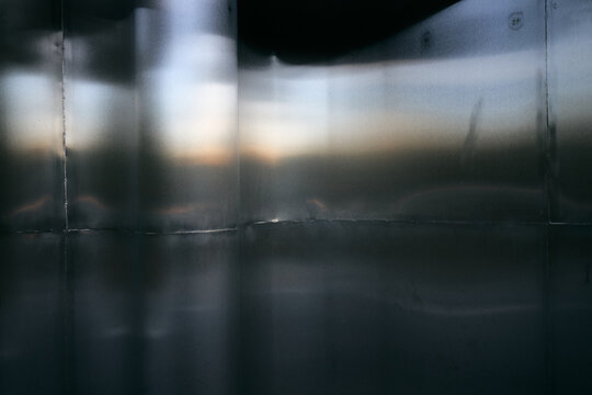 Abstract background of brushed metallic surface with soft light reflections and dark shadows