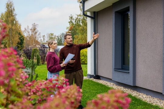 Couple viewing modern new house with landscaped garden. Property inspection before buying. Real estate market