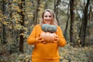 Fototapeta premium Focused woman examining ripe autumn pumpkin in woods - organic crop inspection concept. Small scale farming and quality harvest check. Female farmer looking at harvested squash.