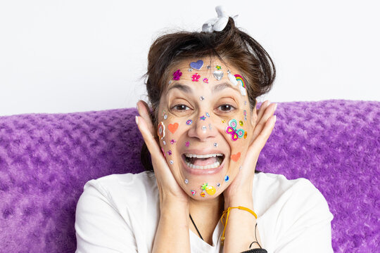 Happy mature middle eastern woman laughing with her hands on her face with colorful stickers and glitter