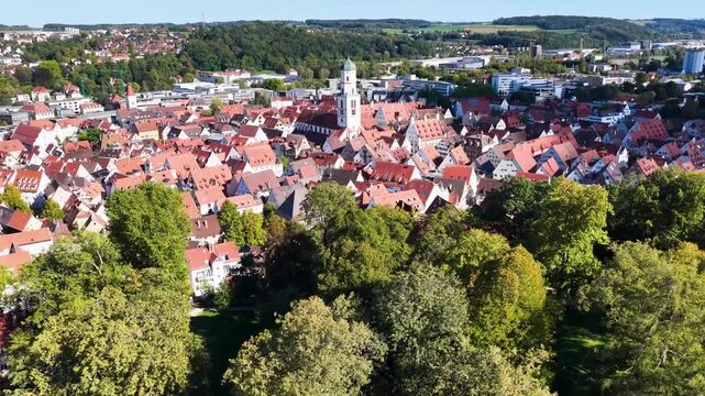 Malerische Panorama-Luftaufnahme von Biberach an der Ri&szlig; mit der historischen Altstadt, markanten Kircht&uuml;rmen und herbstlichen B&auml;umen unter blauem Himmel.