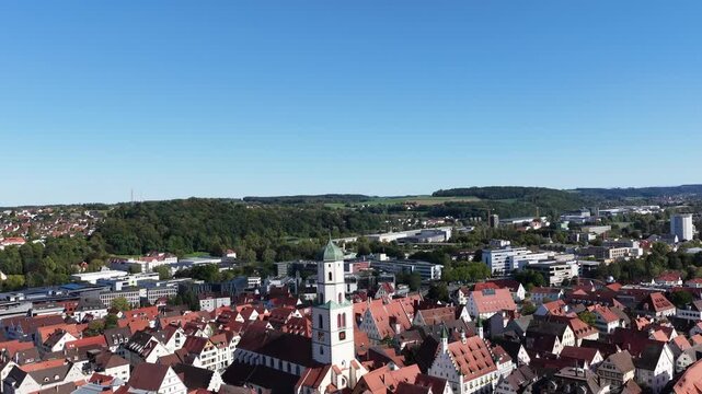 Malerische Panorama-Luftaufnahme von Biberach an der Ri&szlig; mit der historischen Altstadt, markanten Kircht&uuml;rmen und herbstlichen B&auml;umen unter blauem Himmel.
