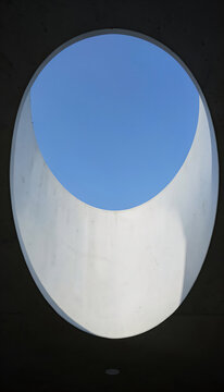 Elliptical concrete skylight opening to blue sky with shadow, architectural interior design banner background.