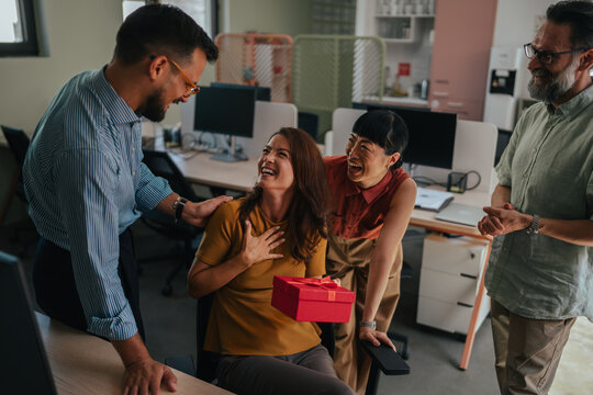 Coworkers celebrating office birthday with surprise gift