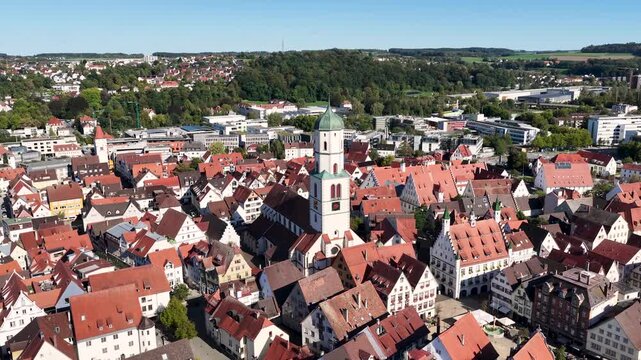 Malerische Panorama-Luftaufnahme von Biberach an der Ri&szlig; mit der historischen Altstadt, markanten Kircht&uuml;rmen und herbstlichen B&auml;umen unter blauem Himmel.