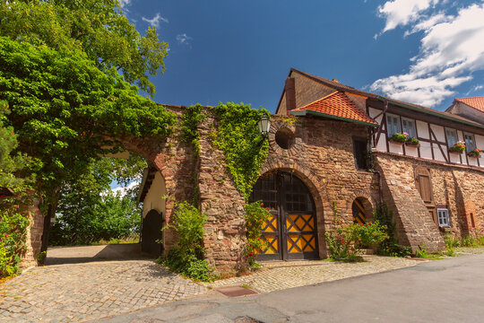 Historic stone buildings with arched gateways, traditional half-timbered architecture and ivy-covered walls in Wernigerode, Germany.