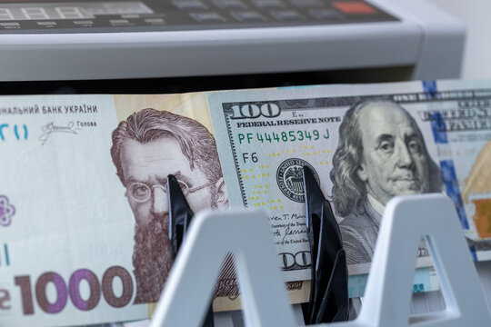USD and UAH banknotes inside counting machine. Economic concept of Ukrainian hryvnia and US dollar exchange rate, currency market trading, financial reserves and valuation. Close-up.