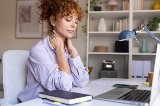Woman suffering from neck pain at office desk