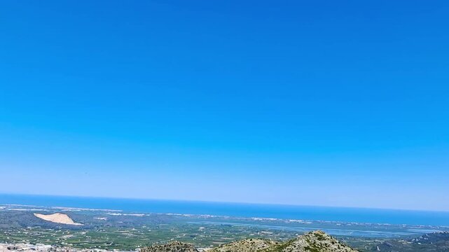Slow motion POV driving shot descending from the scenic Puerto de Vall de Ebo mountain pass towards Pego town. Beautiful panoramic view of the Mediterranean coastline in Spain.