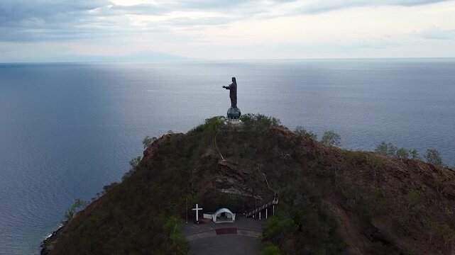 Aerial view rising over Cristo Rei statue overlooking ocean in capital city Dili, Timor-Leste, Southeast Asia