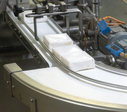 Industrial packaging line for Pont-l'&Eacute;v&ecirc;que soft French cheese on Normandy farm, conveyor belt machinery for automated processing and distribution of traditional French dairy products.