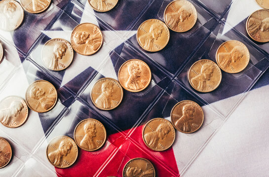 Isolated photo of USA 1 cent coins collection in plastic holder album sheets on american flag backdrop.