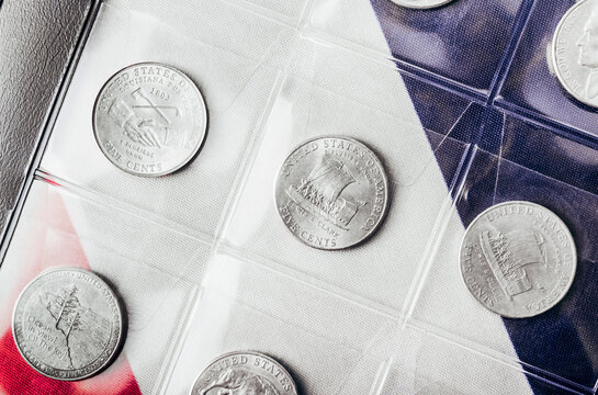 Isolated photo of commemorative USA 5 cent coins collection in plastic holder album sheets on american flag backdrop.
