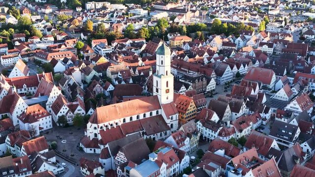 Malerische Panorama-Luftaufnahme von Biberach an der Ri&szlig; mit der historischen Altstadt, markanten Kircht&uuml;rmen und herbstlichen B&auml;umen unter blauem Himmel.