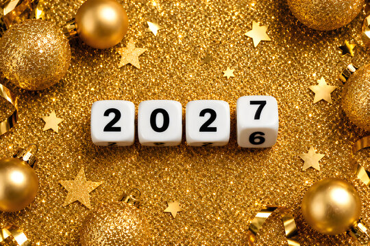 2026 changing to 2027 on dice with christmas glitter golden background for new year change concept