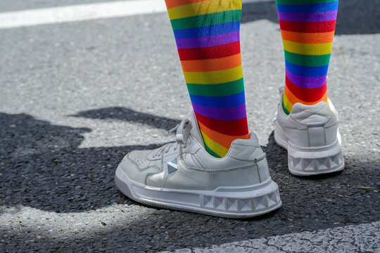 Close-up of legs wearing rainbow pride socks and white sneakers outdoors, symbol of LGBTQ+ freedom, inclusion, and diversity