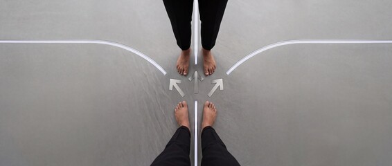 Fototapeta premium Minimalist overhead view of two people standing at a symbolic crossroads with glowing arrows and paths, representing business decision making, life choices, and strategic career directions.